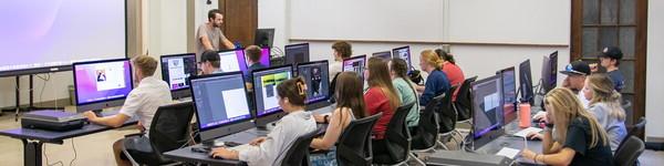 多媒体教室的广阔视野，有几台大型电脑显示器，学生们正在做项目.